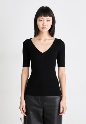 Maglione lavorato a maglia nero con scollatura a V e maniche corte, caratterizzato da una silhouette aderente e texture a coste, abbinato a pantaloni in pelle.
