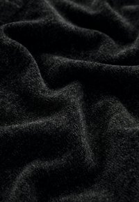 Mustrikate mustriga, pehmea ja tekstuuriga pind, näidates rikkalikku ja tumedat värvi ning õrnu laineid, mis viitavad paksusele ja soojusele.