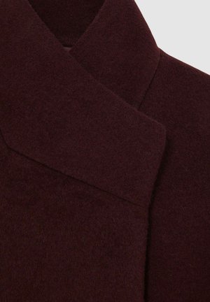 Burgundska volnena plašč z teksturirano površino, ki ima sodoben oblikovan ovratnik in čiste linije za elegantno silhueto.