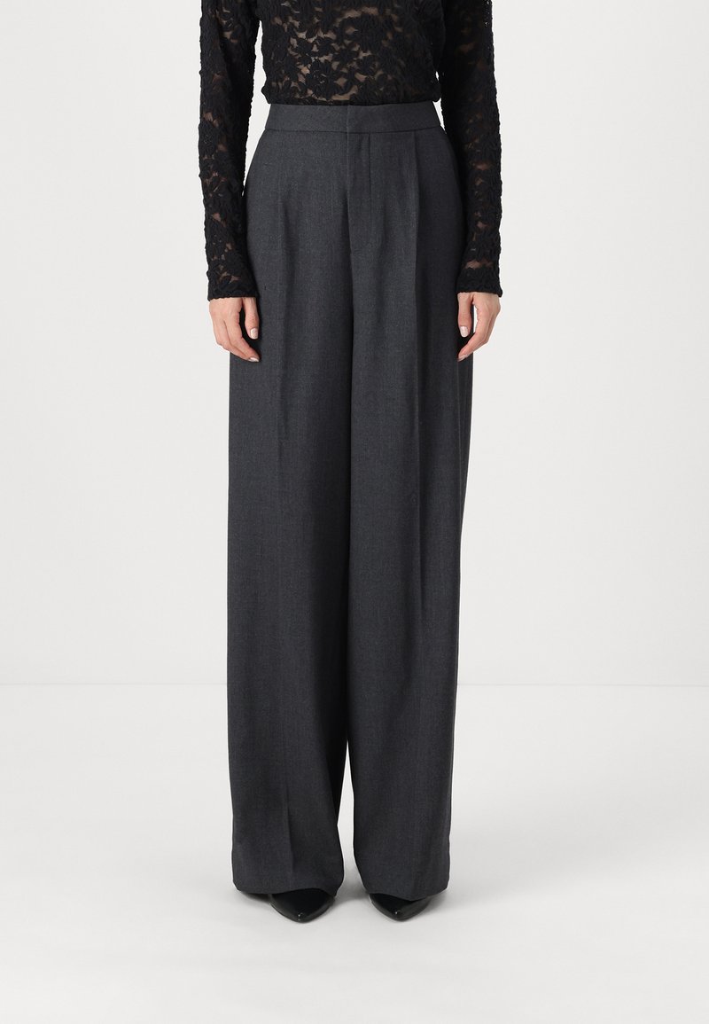 Wide-legged trousers in dark gray fabric, featuring a high waist, subtle texture, and tailored pleats. Worn with a black lace top.