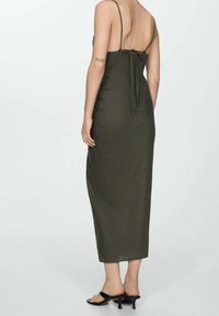 Olivengrünes, ärmelloses Midikleid mit tiefem Rückenausschnitt, dünnen Trägern und einem Bindeband in der Taille. Glatte Textur und leichter Stoff.