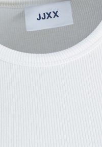 Vit ribbad t-shirt med rund halsringning. Har en etikett med "JJXX" i mörkblått. Tyget verkar texturerat och något elastiskt.