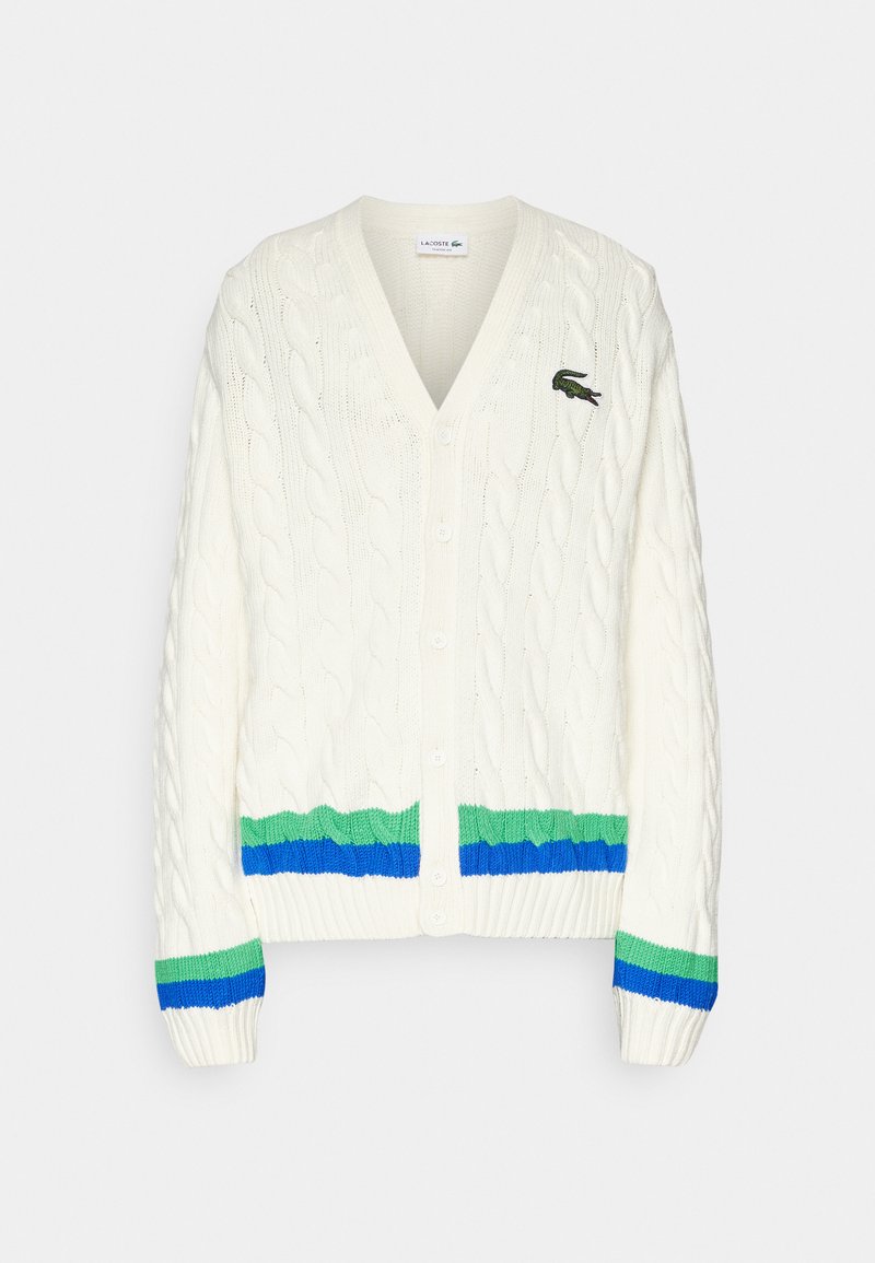 Cardigan blanc en maille torsadée avec un col en V, présentant un ourlet et des poignets rayés verts et bleus, ainsi qu'un petit logo vert sur la poitrine.