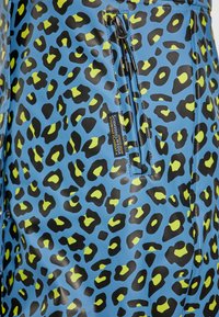 Mėlynas vandeniui atsparus audinys su juodu ir neoniniais geltonais leopardų raštais. Yra užtrauktuku užsegama kišenė su kontrastingais metaliniais detalėmis.