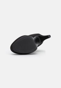Chaussure à talon haut noire avec un dessus lisse, un bout pointu et une semelle en caoutchouc texturée avec un motif nervuré.