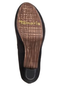 Svart mockaskosula med en strukturerad brun botten, präglad logotyp "Tamaris", och grepplinjer för fäste. Platt design med flexibel material.