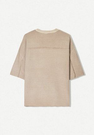 Beige, kurzärmliges Oberteil aus einem weichen, texturierten Stoff. Es hat einen runden Ausschnitt und sichtbare Nahtdetails an den Schultern und am Rücken.