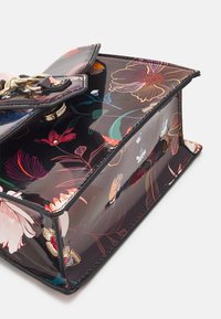 Blommig handväska med en blank svart yta, prydd med flerfärgade blommor och fjärilsmönster, guldfärgade beslag och en strukturerad design.