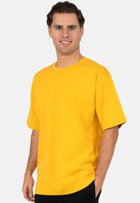T-shirt en coton jaune à manches courtes, avec un col rond, un ourlet droit et une coupe décontractée. Texture lisse, sans motifs ni accents visibles.