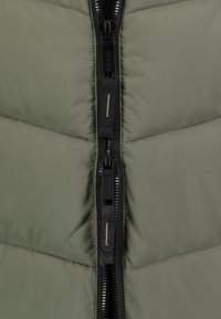 Olijfgroen pufferjack met een centrale dubbele rits, gestikt patroon en zwarte ritsbeslag met logo-detail.