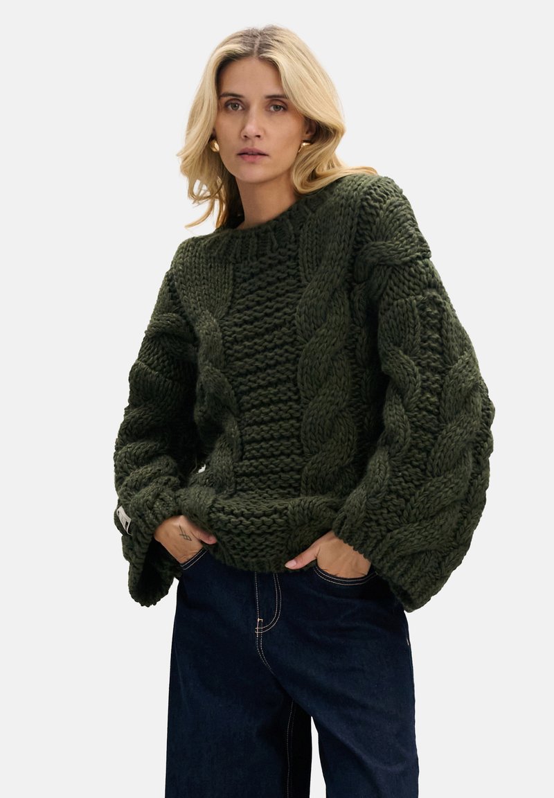 Sweter z dzianiny w ciemnozielonym kolorze z grubym wzorem warkoczowym, szerokimi rękawami i okrągłym dekoltem; fakturowana tkanina dodaje wizualnego uroku.