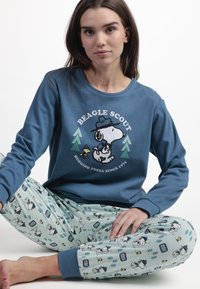 Sudadera de algodón azul con gráfico de Snoopy y el texto "Beagle Scout"; pantalones de pijama verde menta con dibujos de perros de caricatura y patrones de árboles.