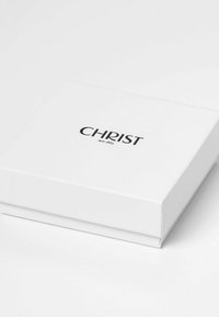 Hvid rektangulær boks med sort tekst "CHRIST siden 1863" på låget, placeret på en hvid overflade.