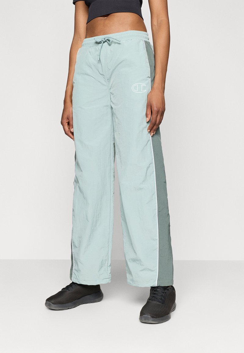 Šviesiai žali, plačių kojų kelnės, pagamintos iš tekstūruotos, lengvos medžiagos, su raišteliu reguliuojamu juosmeniu ir baltais šonų dryžiais bei logotipu.