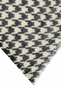 Black and white houndstooth fabric with fringed edges, shown in a close-up angled view.
