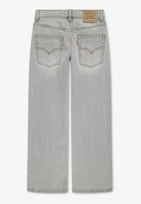 Τζιν γκρι με ίσια γραμμή, διαθέτοντας δύο πίσω τσέπες και αντίθετες ραφές. Δερμάτινο μπραντζάκι στη μέση.