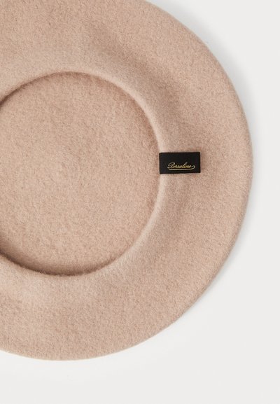 Růžový filcový klobouk kulatého tvaru, s černou etiketou se zlatým písmem. Měkká textura a hladký povrch.