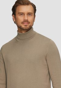 Beżowy sweter z kołnierzem typu golf, prążkowana tekstura, dopasowany krój, średnia grubość, z wysokim kołnierzem. Brak widocznych wzorów i elementów metalowych.