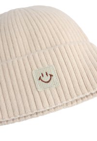 Beanie lavorato a maglia color beige chiaro con texture a coste. Presenta una toppa quadrata con un volto sorridente. Tessuto morbido e design elastico per il comfort.