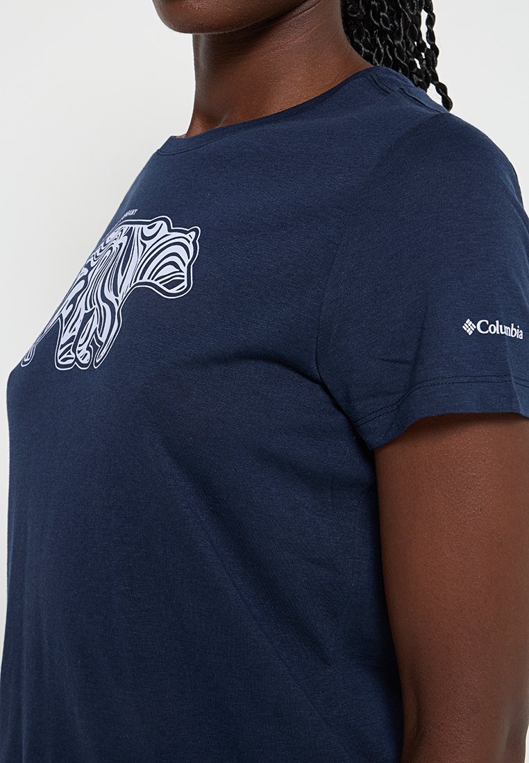 T-shirt en coton bleu marine avec un graphique abstrait d'ours blanc sur le devant, manches courtes et un logo sur la manche droite.