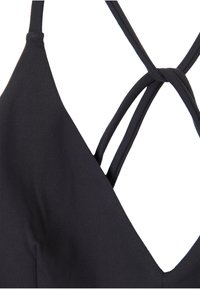 Black camisole with a V-neck design and crisscross back straps. Made from soft fabric, featuring a smooth texture with minimal seams.