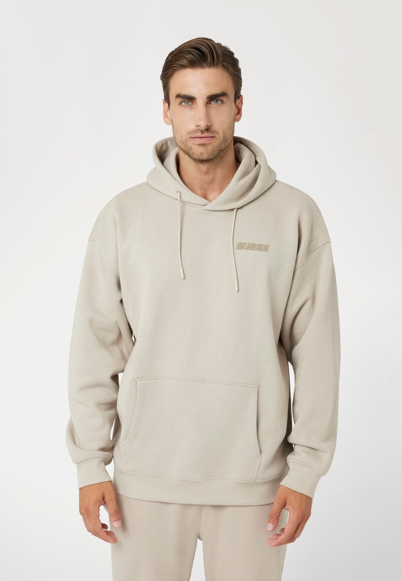 Šviesiai ruda gobtuvinė palaidinė su didele priekyje esančia kišene, sutraukiamomis virvutėmis ir subtiliu logotipu ant krūtinės. Minkšta medžiaga, laisvas siluetas.