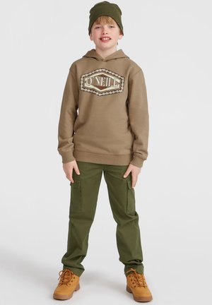 Bruine hoodie met grafisch logo, groene cargo broek en tan laarzen. Accessoires zijn onder andere een groene beanie. Effen kleuren en casual ontwerp.