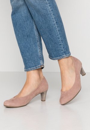 Roze suède pumps met een ronde neus en een korte, gestructureerde blokhak. Draag ze bij blauwe omgeslagen jeans. Glad oppervlak, minimalistisch ontwerp.