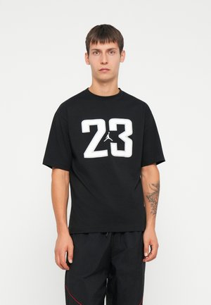 Czarna koszulka z krótkim rękawem z dużą białą grafiką "23" oraz logo Jumpman na klatce piersiowej; wykonana z bawełny, z okrągłym dekoltem.