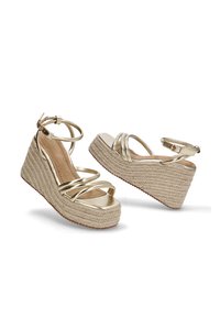 Sandalias de cuña doradas con tiras y una plataforma de cuerda texturizada, con una correa de tobillo asegurada, que cuentan con un upper suave parecido a cuero y suela plana.