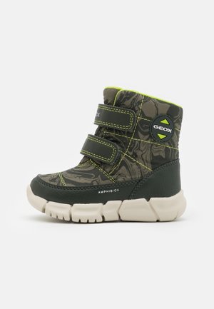 Botte d’hiver enfant verte et noire avec deux bandes velcro, motif camouflage, semelle blanche épaisse et logo Geox sur le côté.