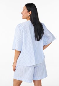 Completo loungewear a strisce blu e bianche in cotone, composto da una maglietta corta e ampia a maniche corte e pantaloni corti abbinati con una vestibilità rilassata.