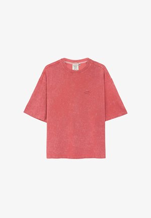 Czerwona koszulka z krótkim rękawem o luźnym kroju, wykonana z miękkiej bawełny, z subtelnym logo na piersi i lekko wyblakłą teksturą.