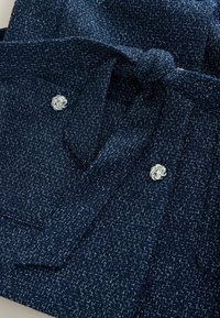 Granatowa teksturowana tkanina z wzorem tkanym, z tkaninowym paskiem i srebrnym dekoracyjnym guzikiem z motywem węzła.