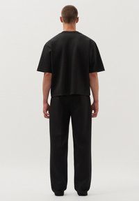 Zwarte kortlijf top gecombineerd met losse zwarte broek, met een strakke vormgeving, gladde textuur en een relaxte pasvorm.