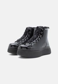 Botas de tornozelo de couro sintético negro com sola robusta e texturada, forro suave e ilhós de metal para os atacadores. Logotipo estampado no tornozelo.