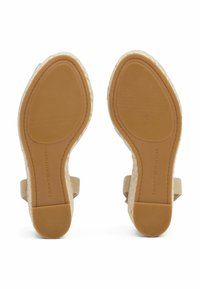 Sandali espadrillas beige con suola in gomma testurizzata, tomaia intrecciata e cinturini alla caviglia. Dettaglio del logo impresso sulla suola.