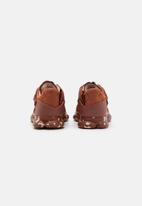 Sneaker in suede e pelle marrone con suola in gomma testurizzata, caratterizzata da un motivo maculato e supporto alla caviglia imbottito per il massimo comfort.