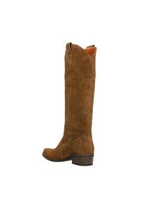 Bottes montantes en daim marron avec un bout rond, un petit talon en bois et des coutures décoratives sur le dessus, présentant un bord supérieur légèrement courbé.