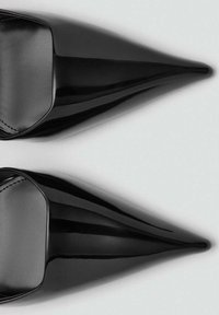 Chaussures à talons hauts en cuir verni noir, à bout pointu, avec une forme élégante et une texture lisse, présentant un design minimaliste et un dos ouvert.