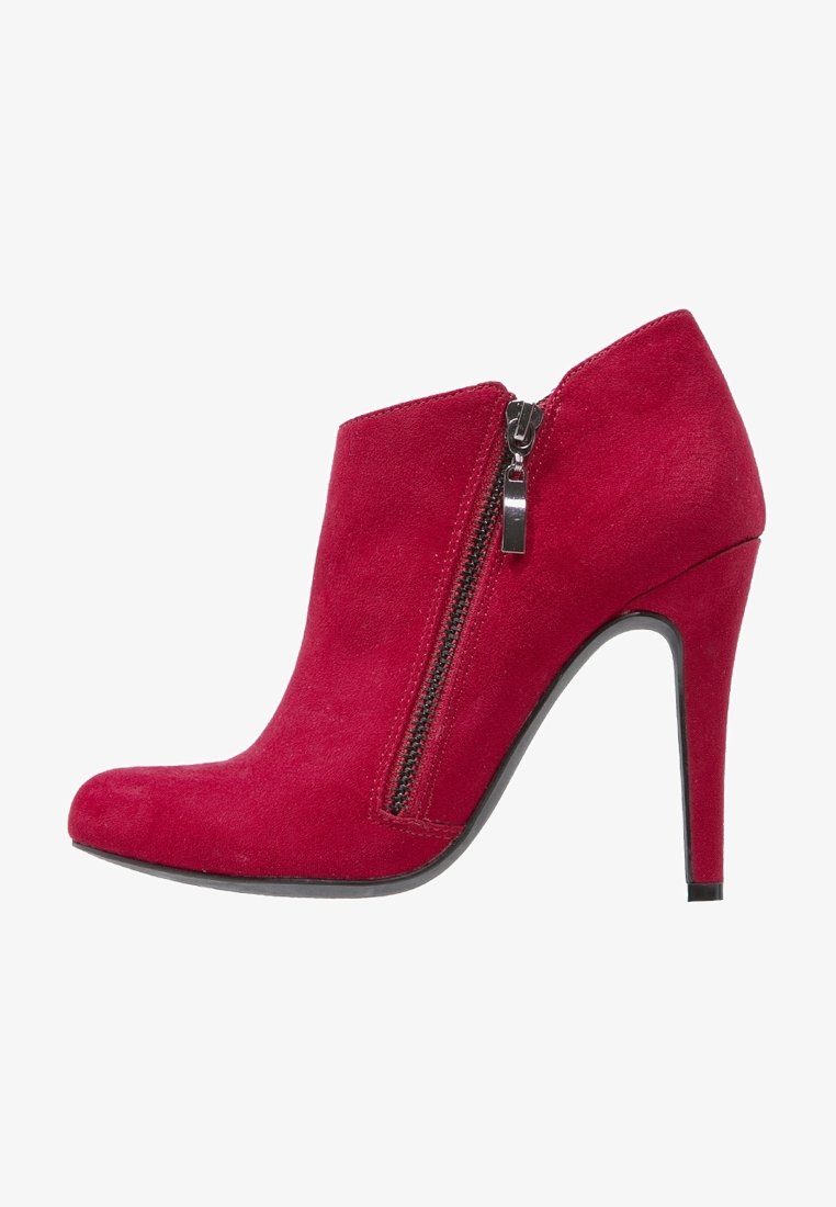 Bottine en daim rouge avec un bout effilé, un talon aiguille haut et une fermeture éclair latérale. La texture lisse met en valeur le design général.