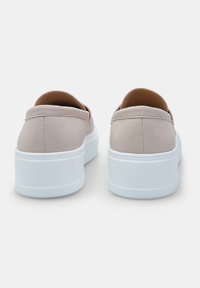 Beige sintētiskie slip-on apavi ar gludu virsmu, balts platformas zole un apaļa papēža. Aizmugures skats, uzsverot šuvju detaļas.