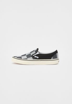 Chaussure Vans slip-on à carreaux noirs et gris avec semelle blanche et bordure latérale noire, présentée sur un fond blanc uni.