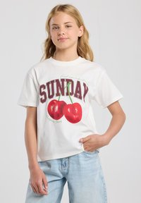 Camiseta de algodón blanca con un diseño gráfico que presenta la palabra "DOMINGO" en color burdeos y una ilustración de cerezas rojas con tallos verdes.