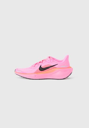 Nike løbesko, der har en lys pink mesh-overdel, sort swoosh-logo, orange accenter, polstret sål og tekstureret gummiydersål.