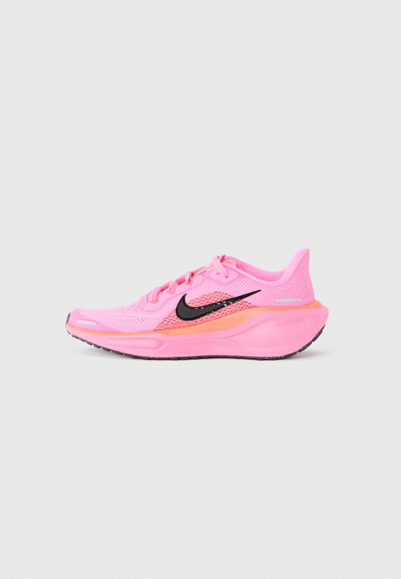 Chaussure de course Nike, avec un dessus en maille rose vif, logo swoosh noir, accents orange, semelle rembourrée et semelle extérieure en caoutchouc texturé.