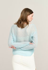 Light blue, mohair sweater with a loose fit, sheer texture, long sleeves, and ribbed cuffs. The back features a slightly see-through design.