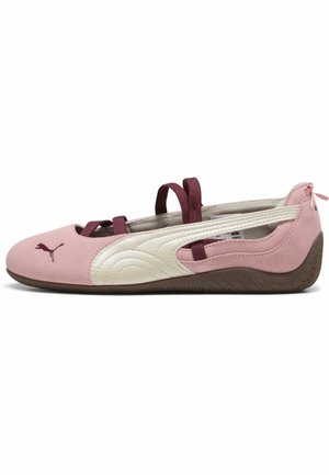 Roze balletflat met witte zijstreep, bordeauxrode elastische bandjes, bruine zool en Puma-logo op de neus, weergegeven in zijaanzicht.