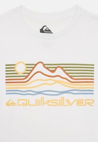 Valkoinen T-paita, jossa on värikäs graafinen kuvaus abstrakteista vuorista, auringosta ja aalloista oranssissa, vihreässä, keltaisessa ja sinisessä. Mukana Quiksilver-logo.