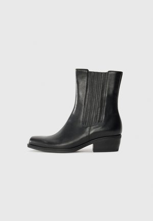 Bottines noires en cuir lisse, dotées de panneaux élastiques côtelés sur les côtés, d'un bout pointu et d'un petit talon carré.
